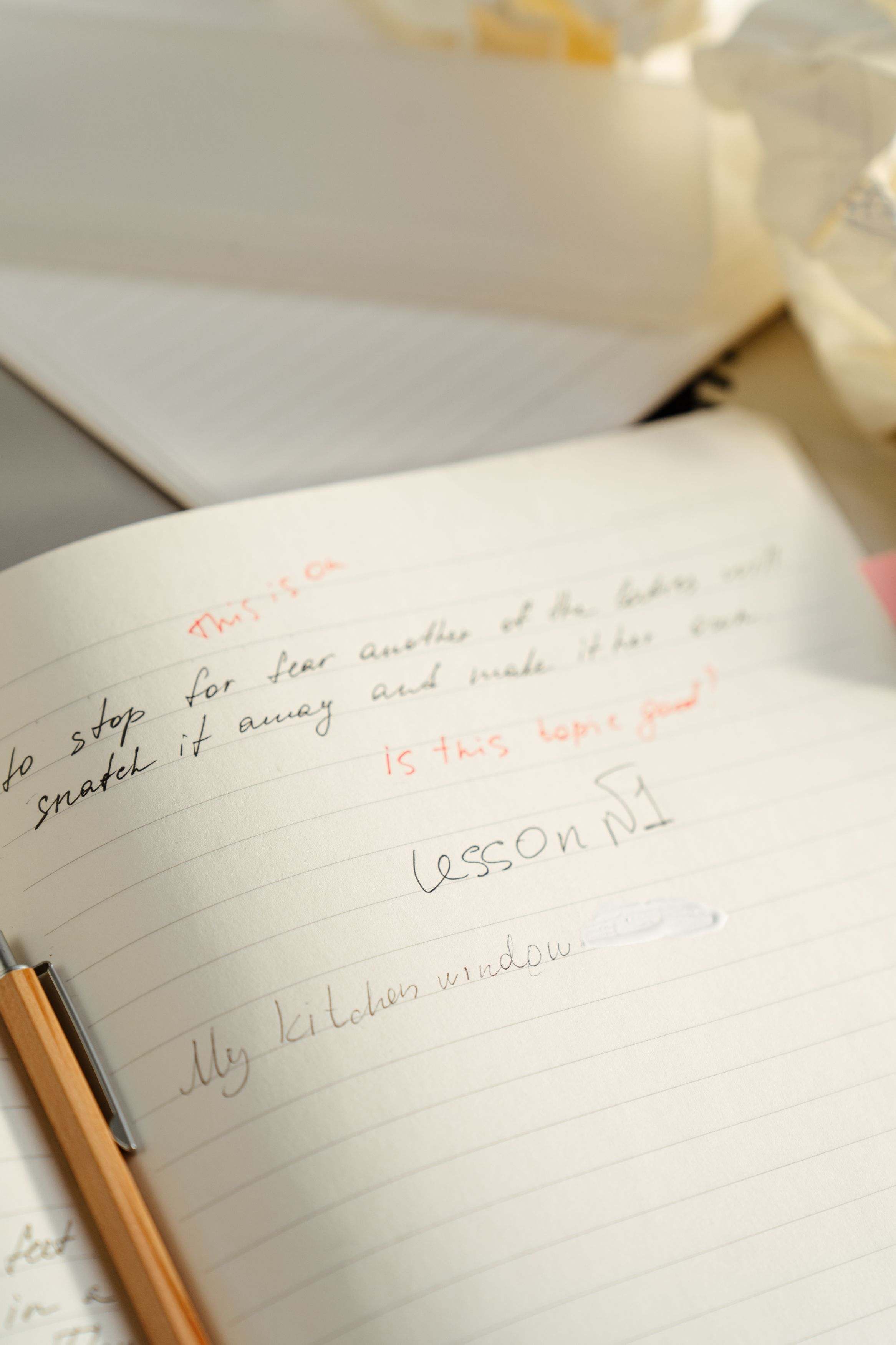 Offenes Notizbuch mit handschriftlichen Einträgen und Stift, seitlich beleuchtet